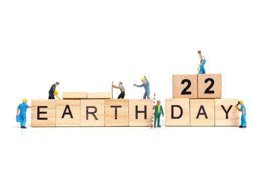 Miniature people : Worker team building word " Earth day " on wooden block with wooden background , Earth day concept