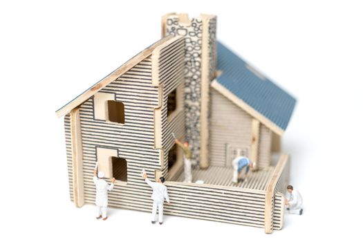 Miniature people : Paintbrush painting wooden house on white background