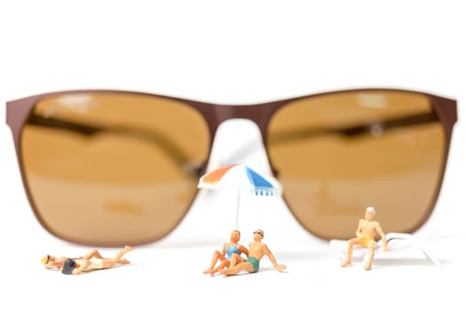 Miniature people wearing swimsuit relaxing on white background