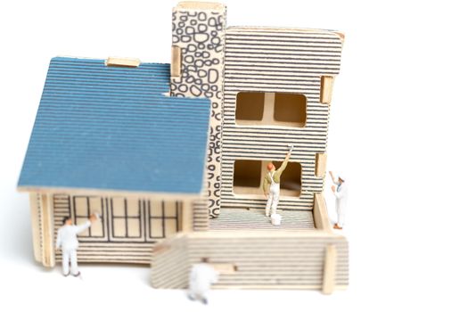 Miniature people : Paintbrush painting wooden house on white background
