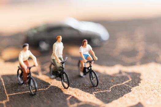 Miniature people travellers with bicycle on World map background
