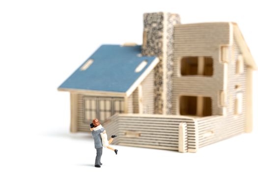 Miniature couple : Couple looking at their dream house on white background