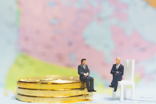 Miniature people: Businessman on stack of coin with world map background , Money and financial business success concept.