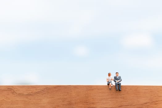 Miniature people:  Business people sitting on wooden floor with blue sky background