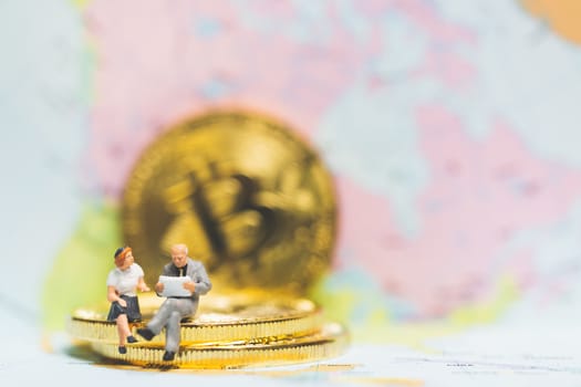 Miniature people: Businessman on stack of coin with world map background , Money and financial business success concept.