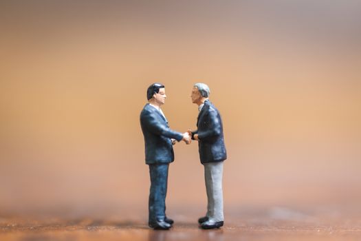 Miniature people Businessman standing on wooden background , Concept of Business leader and teamwork