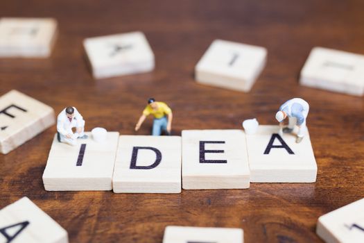 Miniature people standing with wooden block " Idea " words on wooden background