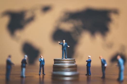 Miniature people: Businessman on stack of coin with world map background , Money and financial business success concept.