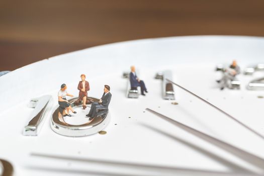 Miniature people Businessman sitting on clock , Concept of Time and Work