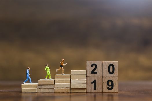 Miniature people  Running on wooden block number 2019 , Healthy lifestyle and sport concepts.