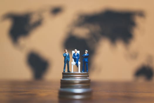 Miniature people: Businessman on stack of coin with world map background , Money and financial business success concept.