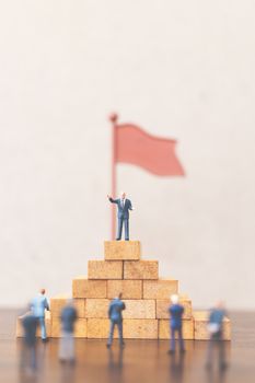 Miniature people Businessman standing on wooden block , Concept of Successful business leader and teamwork