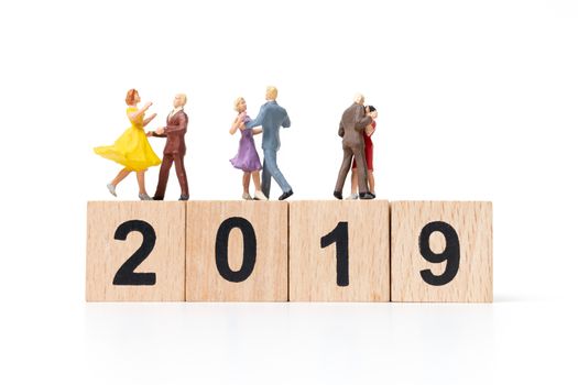 Miniature people dancing on wooden block number 2019. on white background