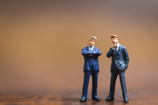 Miniature people Businessman standing on wooden background , Concept of Business leader and teamwork