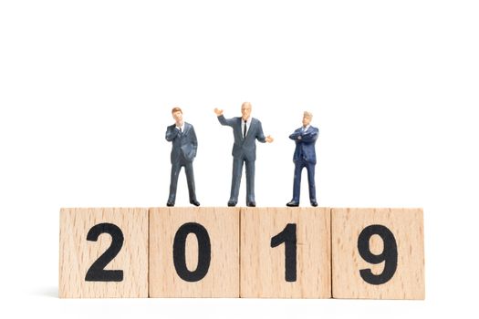 Miniature people : businessman  standing and thinking on wooden block number 2019. on white background