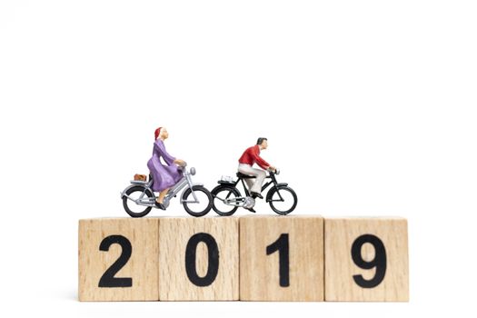 Miniature people : Friend Group ride bicycle with wooden number  2019 , Happy New Year  concept.