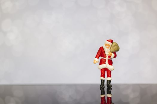 Miniature people : Santa Claus carrying bag  on bokeh  background , Merry Christmas and Happy New Year concept.