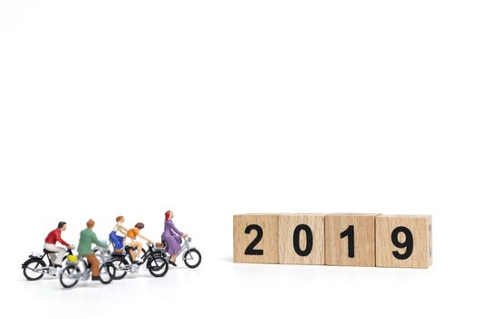 Miniature people : Friend Group ride bicycle with wooden number  2019 , Happy New Year  concept.