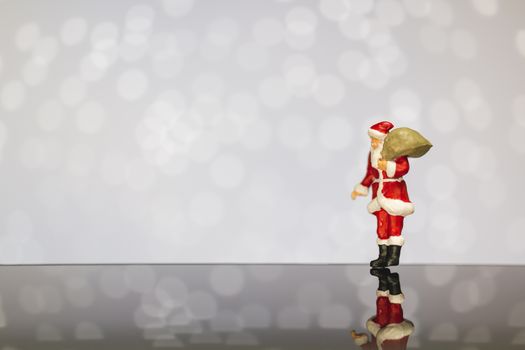 Miniature people : Santa Claus carrying bag  on bokeh  background , Merry Christmas and Happy New Year concept.