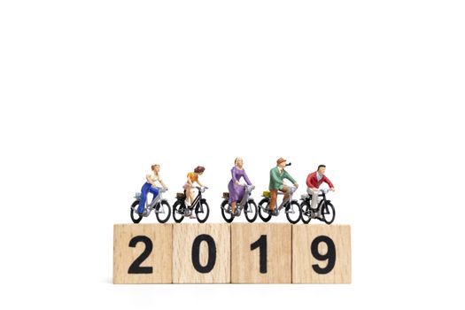 Miniature people : Friend Group ride bicycle with wooden number  2019 , Happy New Year  concept.