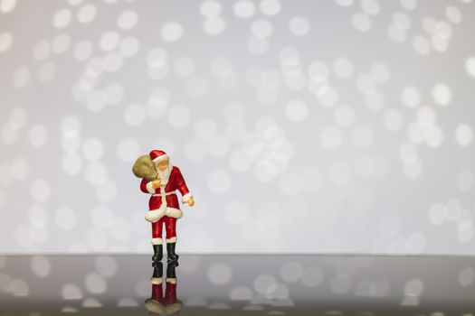 Miniature people : Santa Claus carrying bag  on bokeh  background , Merry Christmas and Happy New Year concept.