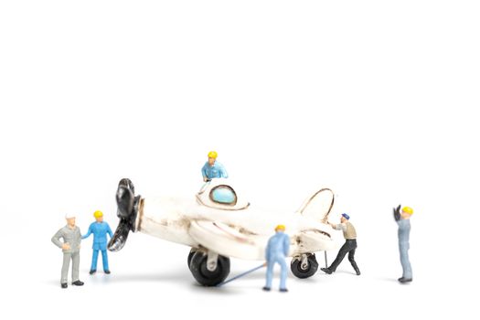 Miniature people : worker team repairing toy airplane on white background