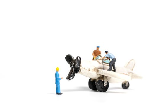 Miniature people : worker team repairing toy airplane on white background