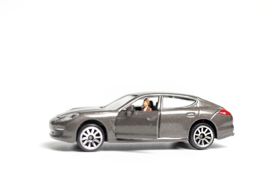 Miniature people sitting on car with copy space on white background 