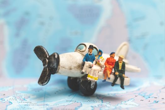 Miniature people sitting on The Airplane with world map background, Travel concept