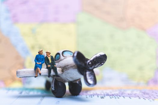 Miniature people sitting on The Airplane with world map background, Travel concept