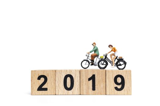 Miniature people : Friend Group ride bicycle with wooden number  2019 , Happy New Year  concept.