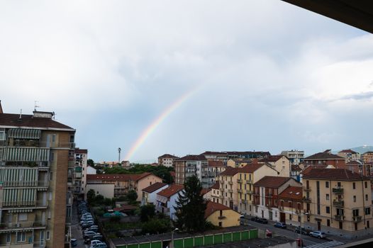 Turin, Piedmont, Italy. June 2020. After a summer storm in the northern suburbs, a rainbow emerges from the roof of a small house on the horizon and embraces the city.