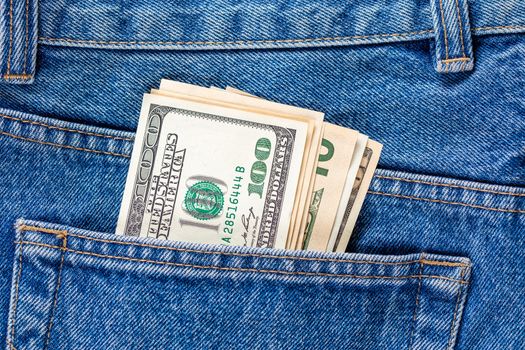 US dollar banknotes in the left rearpocket of blue jeans. Concept of saving money or pocket expenses.