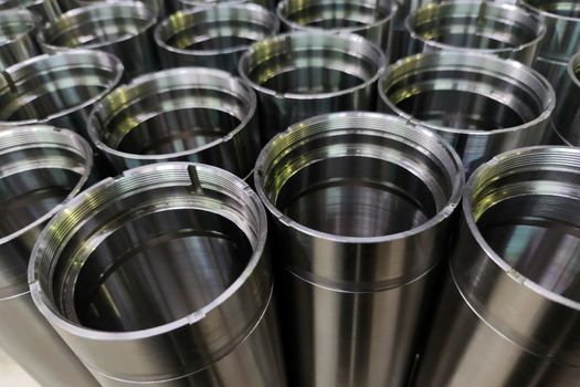 A close-up shot of shiny steel aerospace cnc turned tubes in a batch with selective focus and background blur.