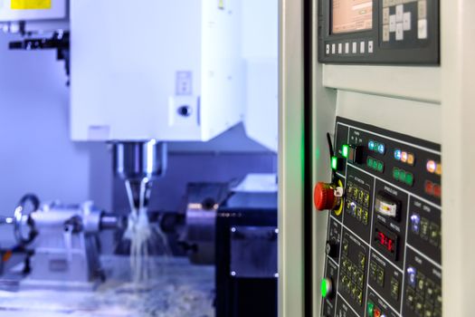 A modern 4-axis cnc vertical milling machine working with water cooling, selective focus on foreground, blur on background,