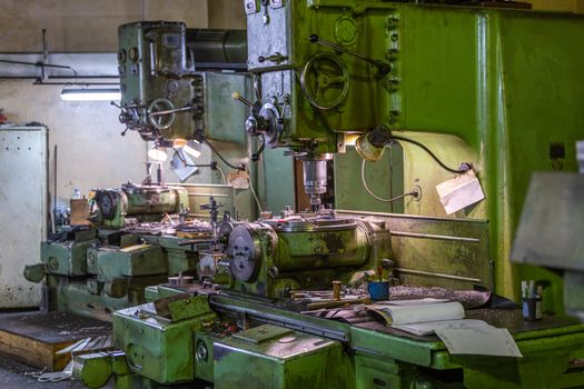 Two old and big soviet vertical 5-axis industrial grade precision vertical milling and boring machines indoors with selective focus and blur.