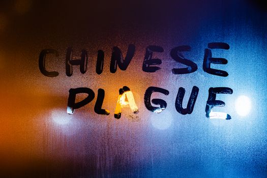 The words chinese plague handwritten on sweat window glass surface at night. Pandemic concept.