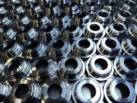 Shiny silver color stainless steel parts background. Regular industrial metal production pattern with selective focus and background blur.