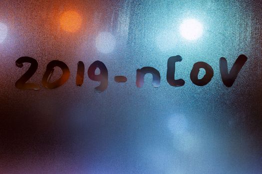 The word 2019-nCoV handwritten on sweat window glass surface at night. Pandemic concept.