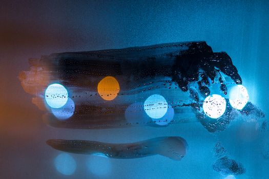 a night wet window glass wiped by hand - dark background and mockup.