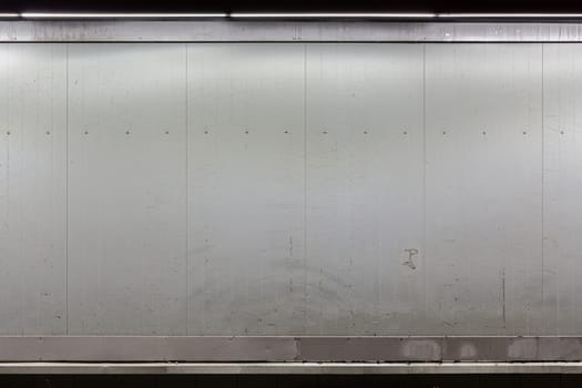 a blank flat white wall with old paint illuminated from above at night.