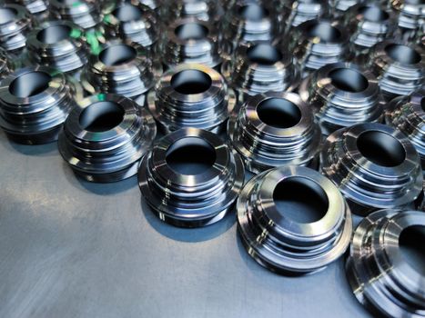 Shiny steel parts background. An edge of metal cnc turning production batch laid bin rows on flat brushed iron surface.