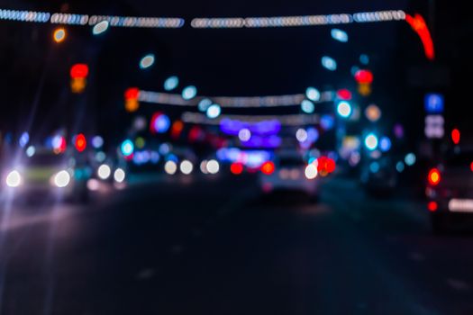 Defocused picture of night street car traffic - view from road. Colorful night life dark background.