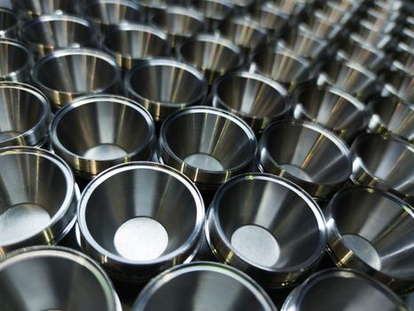 Shiny silver color stainless steel parts background. Regular industrial metal production pattern with selective focus and background blur.