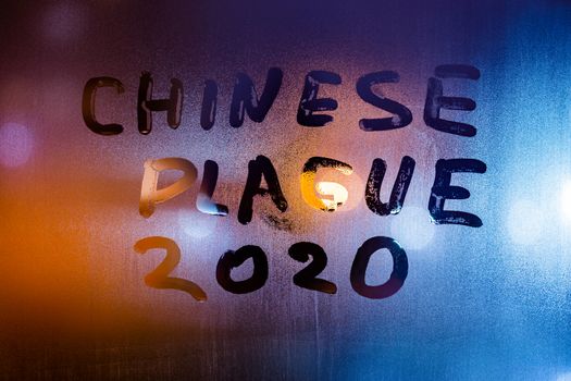 The words chinese plague 2020 handwritten on sweat window glass surface at night. Pandemic concept.