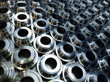 Shiny silver color stainless steel parts background. Regular industrial metal production pattern with selective focus and background blur.