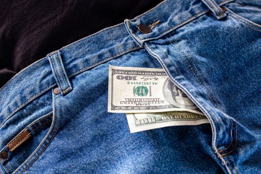 a two hundred dollar bills inside codpiece of blue jeans close-up with selective focus.