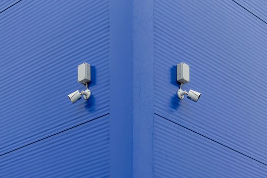 two small white security cameras on blue steel building corner.