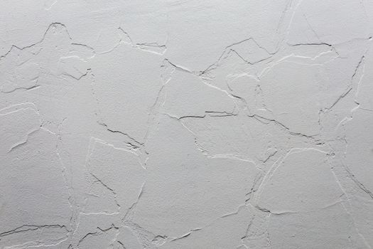 Abstract white unobtrusive background and texture. A plaster wall with old cracked layer under new one. Top-down light direction.