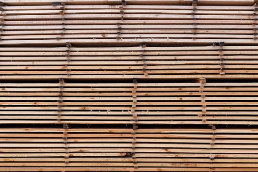 Large stacks of wooden planks full frame flat background. Woodwork industrial storage.